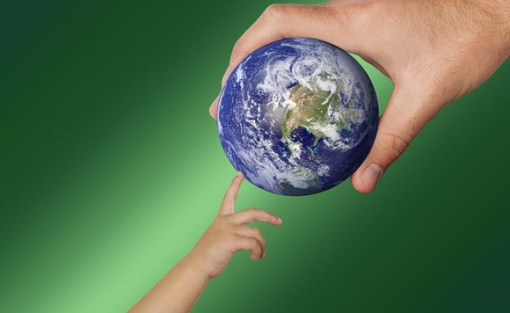 une main d'adulte transmet une planète Terre miniature à une main d'enfant